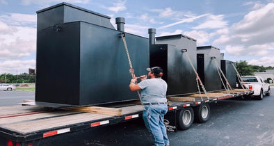 Worker securing REMAINSAFE Steel Safe Shelters to flatbed truck